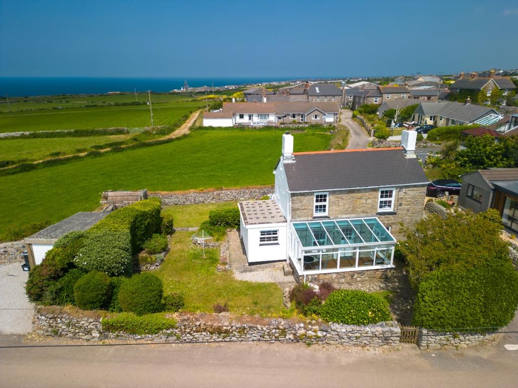 Lot: 62 - DETACHED COTTAGE WITH GARDEN, PARKING AND SEA VIEWS - Drone photo looking down on the property with surrounding views in the background